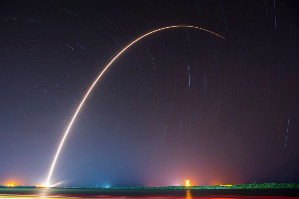A bright missile trail arcs through a starry night sky