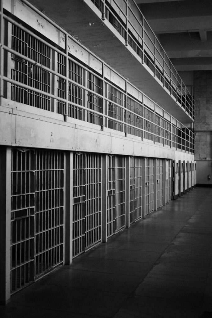 Rows of empty cells along a prison cell block walkway