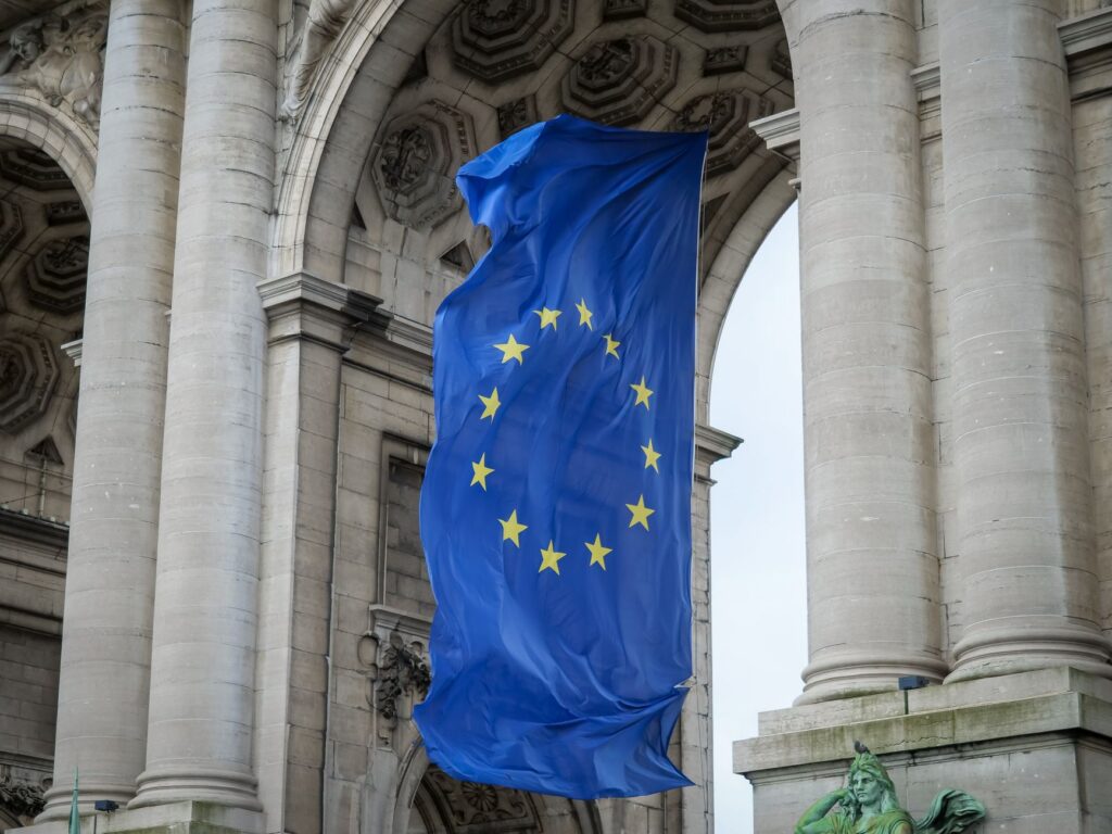 European Union flag flying beneath a stone arch in Brussels