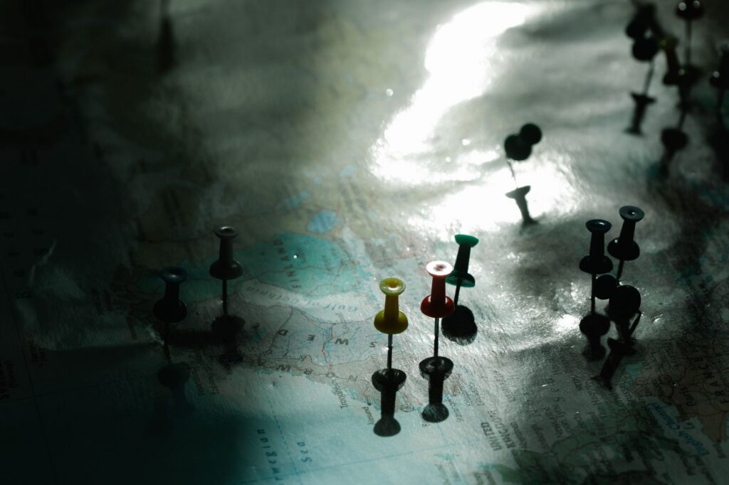 A map with colored pins under dramatic light, representing strategic positions and routes