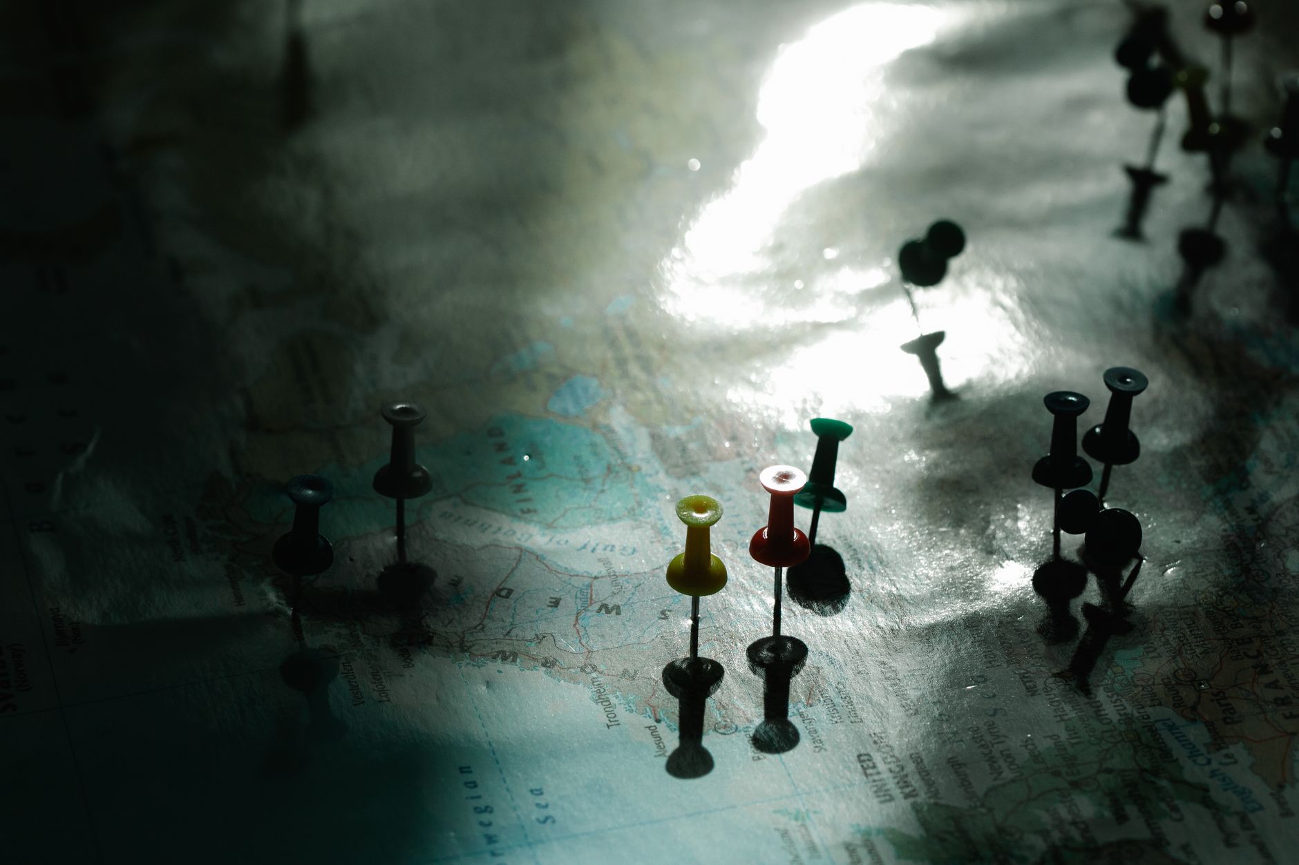 A map with colored pins under dramatic light, representing strategic positions and routes