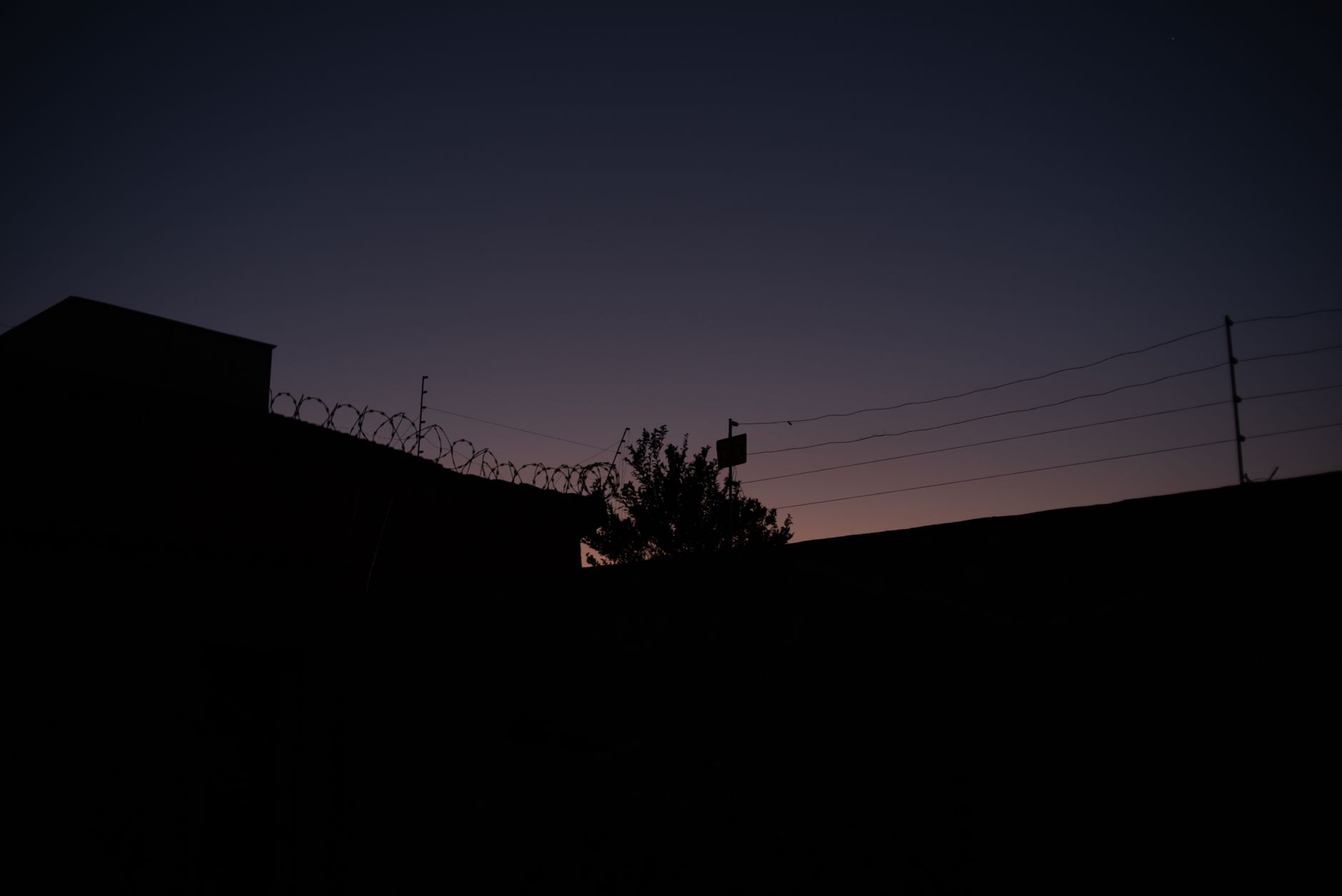 Silhouette of a barbed wire fence against a dramatic sky