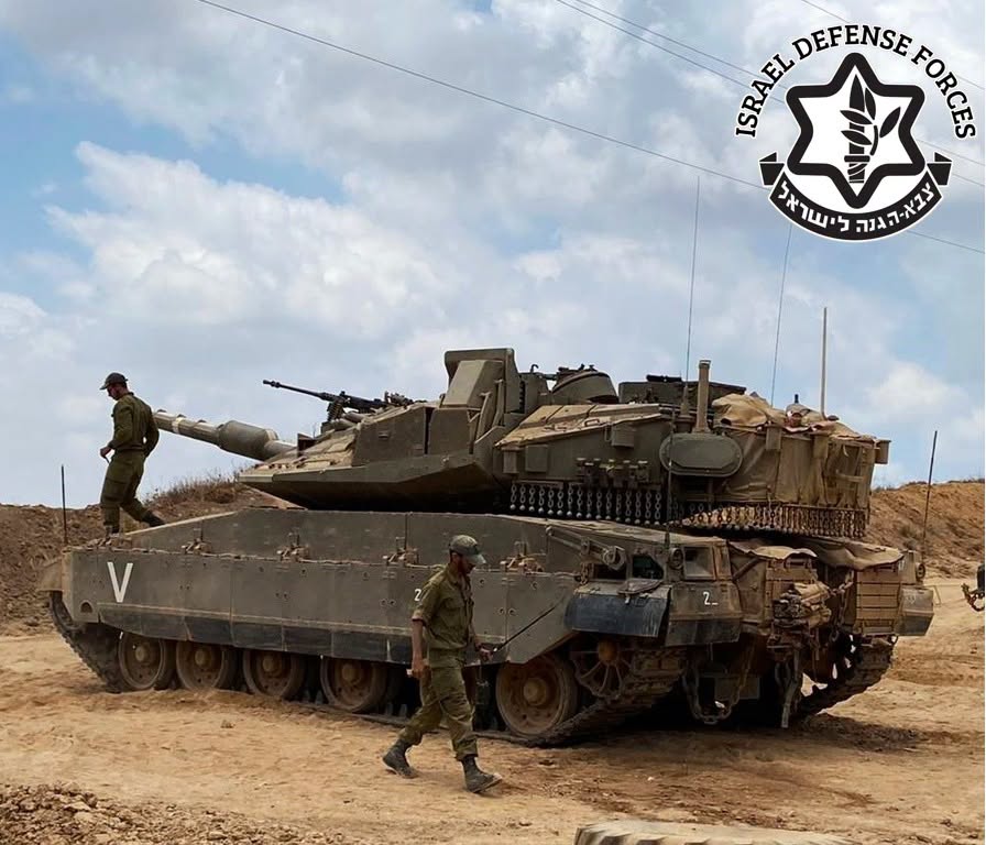 Israeli soldiers beside a Merkava tank, with the Israel Defense Forces emblem