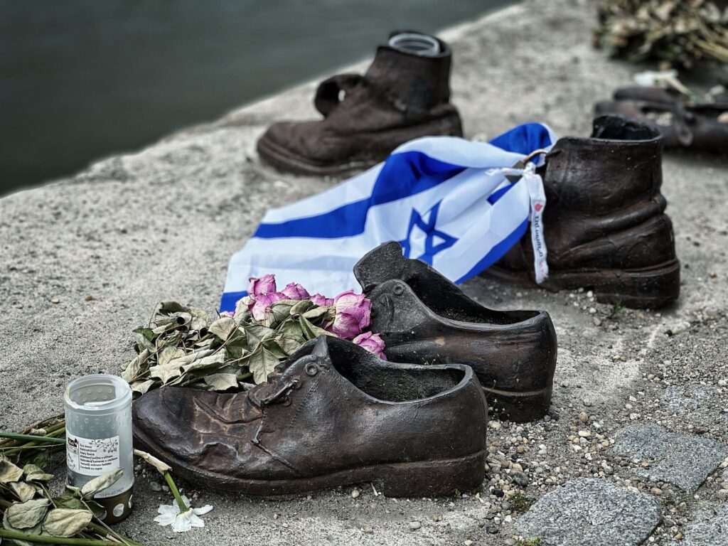 Memorial sculpture of shoes with an Israeli flag and flowers